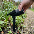 Solar spot light with zoom lens staked in a garden flower bed