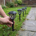 Solar pathway lights being placed along a garden path