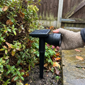 RGB solar spot light staked beside a garden shrub border