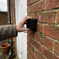 Solar LED wall light fitted to a brick wall by a back door