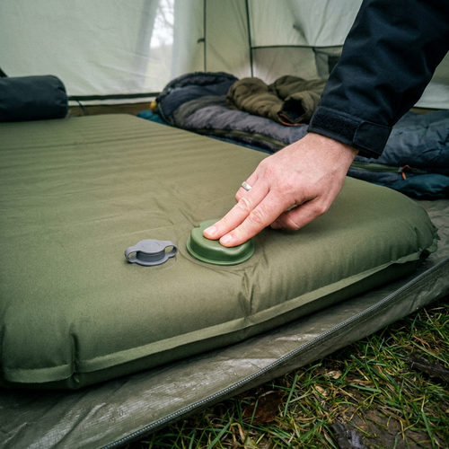 Camping air mattress being inflated with its foot pump in a tent