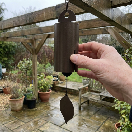 Metal wind bell chime hanging from a pergola