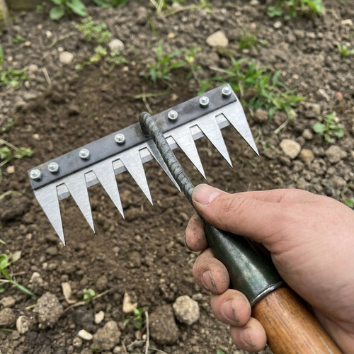 Carbon steel rake head being fitted to a handle over a flower bed